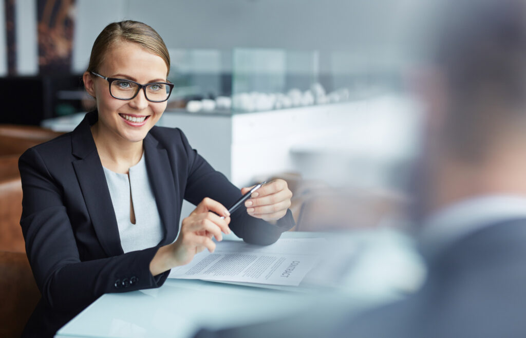 Business woman sitting at her desk and smiling at a colleague.